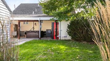 A residential backyard with a covered patio, a barbecue grill, and a shed.