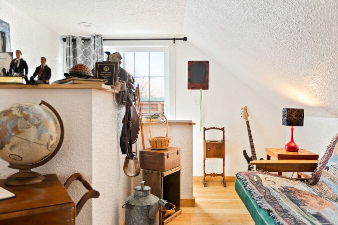 Una habitación acogedora con un escritorio de madera, un globo terráqueo y una guitarra.