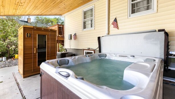 A hot tub in front of a house with a wooden deck and a small shed. - Bo’s Old West Abode with Hot Tub and Sauna (Billings)