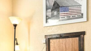 Ein Zimmer mit Kaminofen, einem gerahmten Bild eines Gebäudes mit einer amerikanischen Flagge, einem schwarzen Lederstuhl und einer Stehlampe.