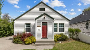 A white single-story house with a red door and a small porch.