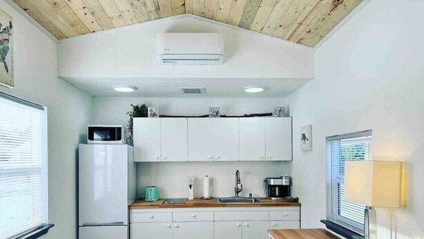Uma cozinha compacta com armários brancos, micro-ondas embutido e máquina de café.