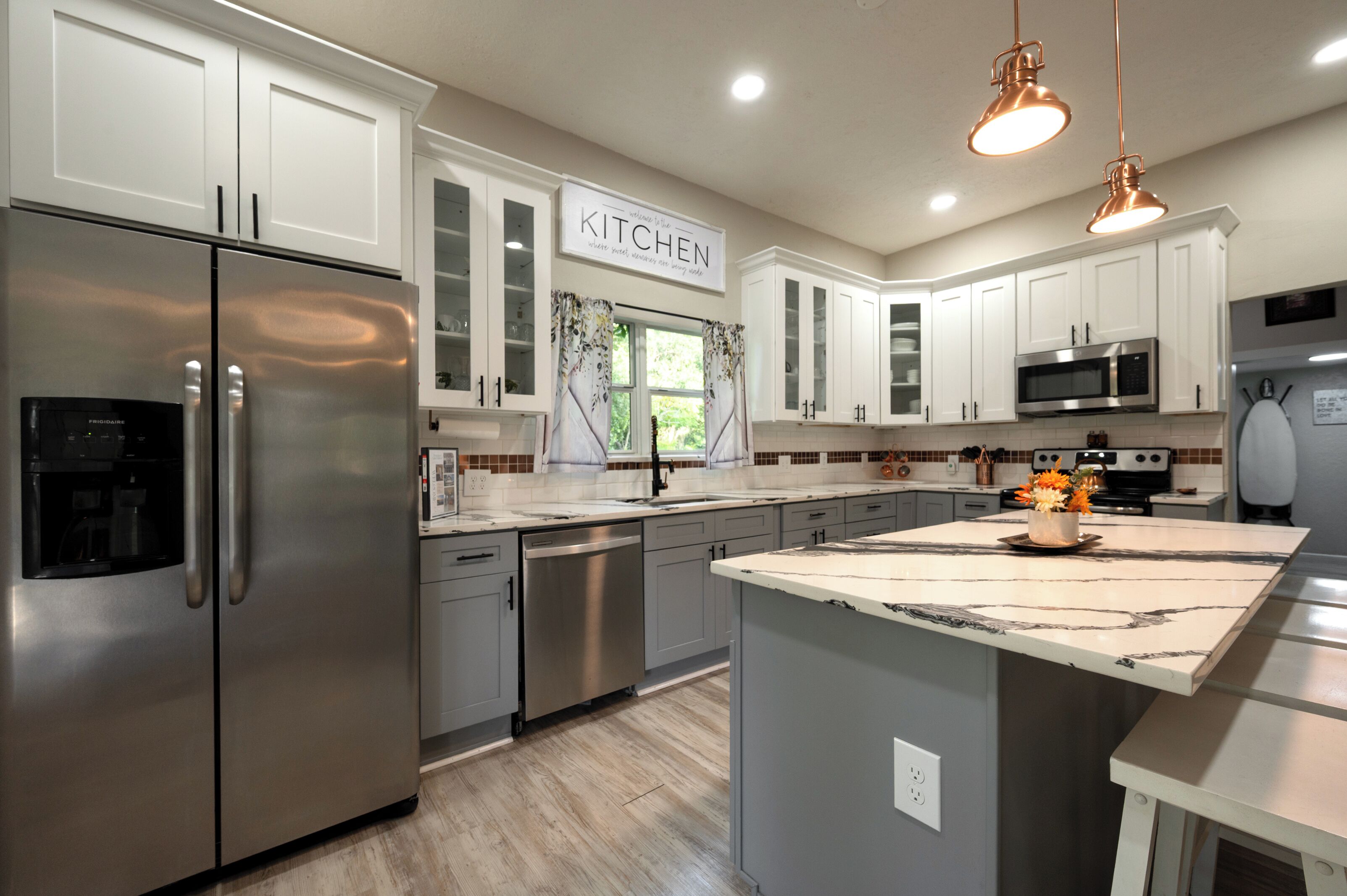 A modern kitchen with stainless steel appliances, white cabinetry, and a marble island.