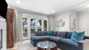 A modern living room with a grey sectional sofa, a glass coffee table, and a patterned rug. - CDM Beach House (Newport Beach)