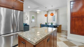 A kitchen with granite countertops, stainless steel appliances, wooden cabinets, and pendant lighting. - CDM Beach House (Newport Beach)