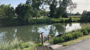 A calm river with a wooden dock and a small boat. - Le Refuge des Bateliers (Arçais)