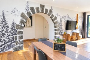 Un espace repas avec une table en bois, des chaises et un panneau d’accueil.