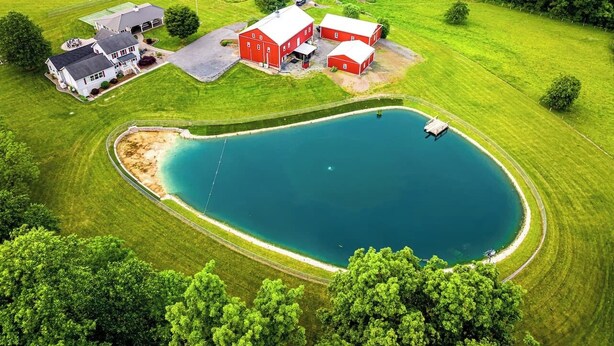An aerial view of a property with a large pond, a barn, and a house. - A luxury farm stay with something special for everyone in your group! (Ickesburg)