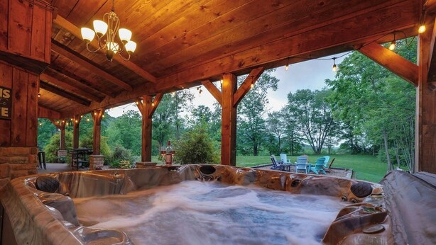 Un espace avec un bain à remous, des poutres en bois et une vue sur l’extérieur.