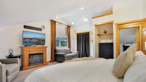 Une chambre d’hôtel avec un grand lit, une télévision, une cheminée, un canapé et une armoire.