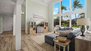 A spacious living room with a large window, a television, and a cozy seating area. - Princeville Home w/Private Pool and Mountain View (Princeville)
