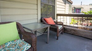 Ein Balkon mit Korbmöbeln und einem Glastisch.