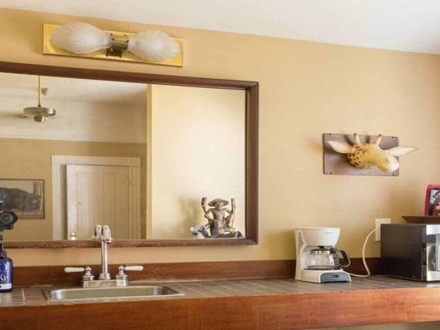A hotel bathroom with a large mirror, a sink, a coffee maker, and a microwave.