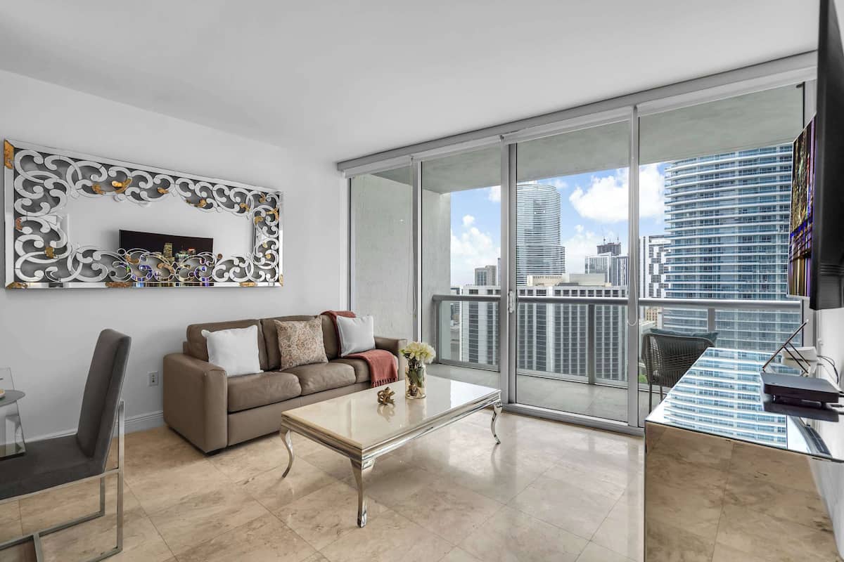 Uma sala de estar moderna com sofá, mesa de centro e uma grande janela com vista para a cidade.