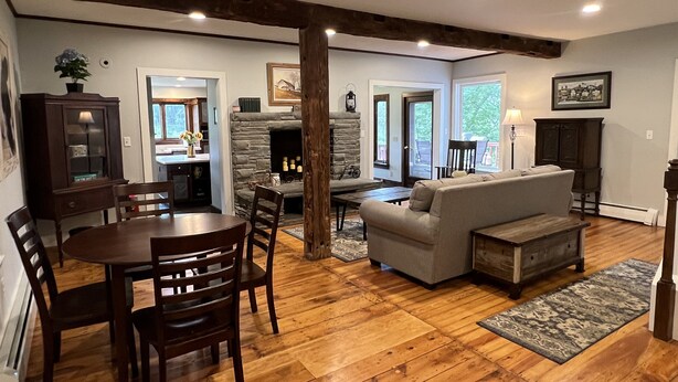 A spacious living area with a stone fireplace, wooden flooring, and a gray sofa. - 5 minutes to Cooperstown Village - New Renovation! (Cooperstown)