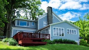 A two-story house with a chimney, a deck, and a large tree in the background. - 5 minutes to Cooperstown Village - New Renovation! (Cooperstown)