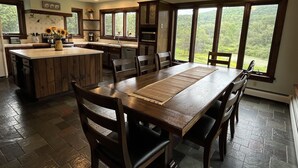 A spacious kitchen with a large island, wooden cabinets, and a dining area with a view of the outdoors. - 5 minutes to Cooperstown Village - New Renovation! (Cooperstown)