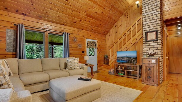 A cozy cabin interior with a sectional sofa, a television, and a fireplace. - Unplug from the daily grind, whether a fun family getaway or a retreat with friends, this cabin is a perfect refuge to unwind and rejuvenate. Brand new Hot Tub! (Elliottsburg)