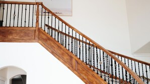 A grand staircase with a wooden handrail and black balusters, leading to an upper floor.