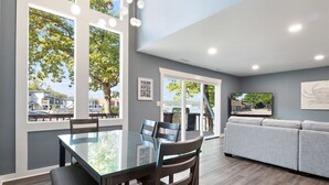 Een moderne keuken met een glazen eettafel, houten stoelen en een grijze bank.