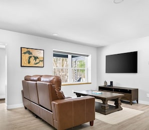 Un salon moderne avec un canapé en cuir, une table basse, un téléviseur et une carte accrochée au mur.