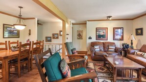 A spacious living room with wooden furniture, a dining area with a wooden table and chairs, and a cozy seating area with a leather couch and armchairs. - Forest Retreat - Hot Tub, Close to Lake (Carnelian Bay)