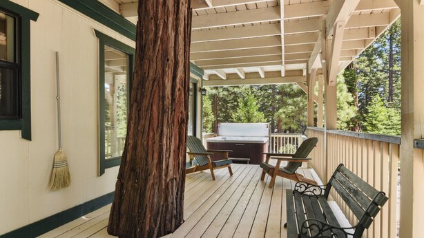 A wooden deck with a large tree trunk, outdoor seating, and a grill. - Forest Retreat - Hot Tub, Close to Lake (Carnelian Bay)