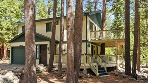 A two-story cabin with a green roof, a front porch, and a staircase leading to a balcony. - Forest Retreat - Hot Tub, Close to Lake (Carnelian Bay)