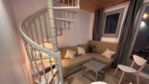Un salon comprenant un escalier en colimaçon, un ensemble de canapés, une table basse et deux fauteuils.