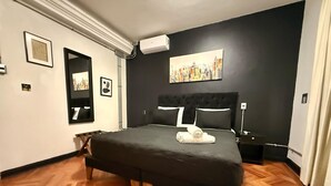 Ein Schlafzimmer mit einem großen Bett, einem schwarzen Kopfteil und einem Gemälde an der Wand.