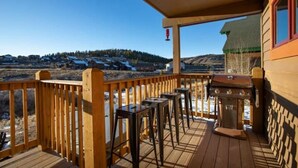 Una terraza de madera con vista a un paisaje nevado y un edificio al fondo.