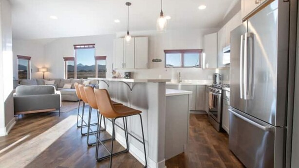 Una cocina moderna con una isla central, electrodomésticos de acero inoxidable y un comedor con taburetes de bar.