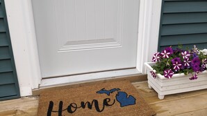 A white door with a doormat that reads "Home" and a blue outline of a state. - Sweet One Bedroom in the heart of the Keweenaw! (Ahmeek)
