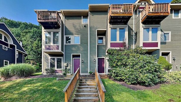 A multi-story residential building with a central staircase, balconies, and a well-maintained lawn. - Villages of Wisp 14 Winding Way by Taylor Made Deep Creek (McHenry)