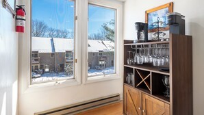 A room with a large window, a fire extinguisher, a wooden cabinet with wine glasses, and a coffee maker. - Villages of Wisp 14 Winding Way by Taylor Made Deep Creek (McHenry)