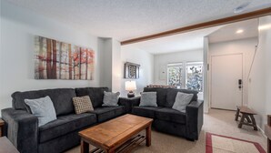 A living room with a sectional sofa, a wooden coffee table, and a large abstract painting on the wall. - Villages of Wisp 14 Winding Way by Taylor Made Deep Creek (McHenry)