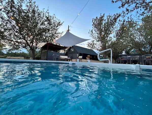 Relax by the pool surrounded by lush trees and enjoy the view of the resort building.