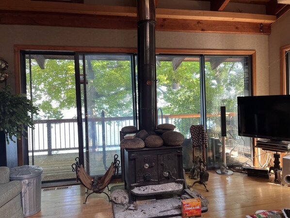Cozy retreat with a traditional wood-burning stove, large windows, and a TV for entertainment.