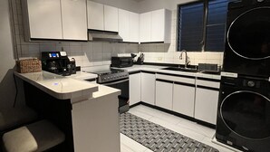 A modern kitchen with white cabinets, a central island, a built-in oven, a microwave, and a coffee maker. - Tropical Oasis 🇻🇮Stunning ocean view, minutes drive to Brewers Beach!🇻🇮🏝 (St Thomas)