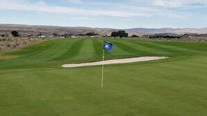 A golf course with a flag, sand bunkers, and distant houses. - New Custom Multi Master + Sleeping Room Golf Course Home w/ Outdoor Living Area  (Mattawa)