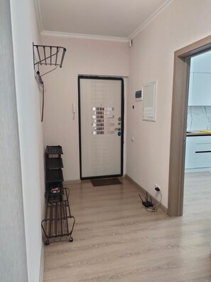 A hallway with a door, a small shelf, and a power outlet.