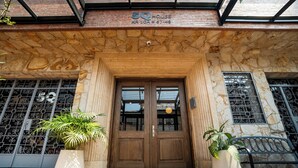 A stone facade with a wooden double door, potted plants, and a metal bench. - 5Q House Quinta Camacho (Bogotá)