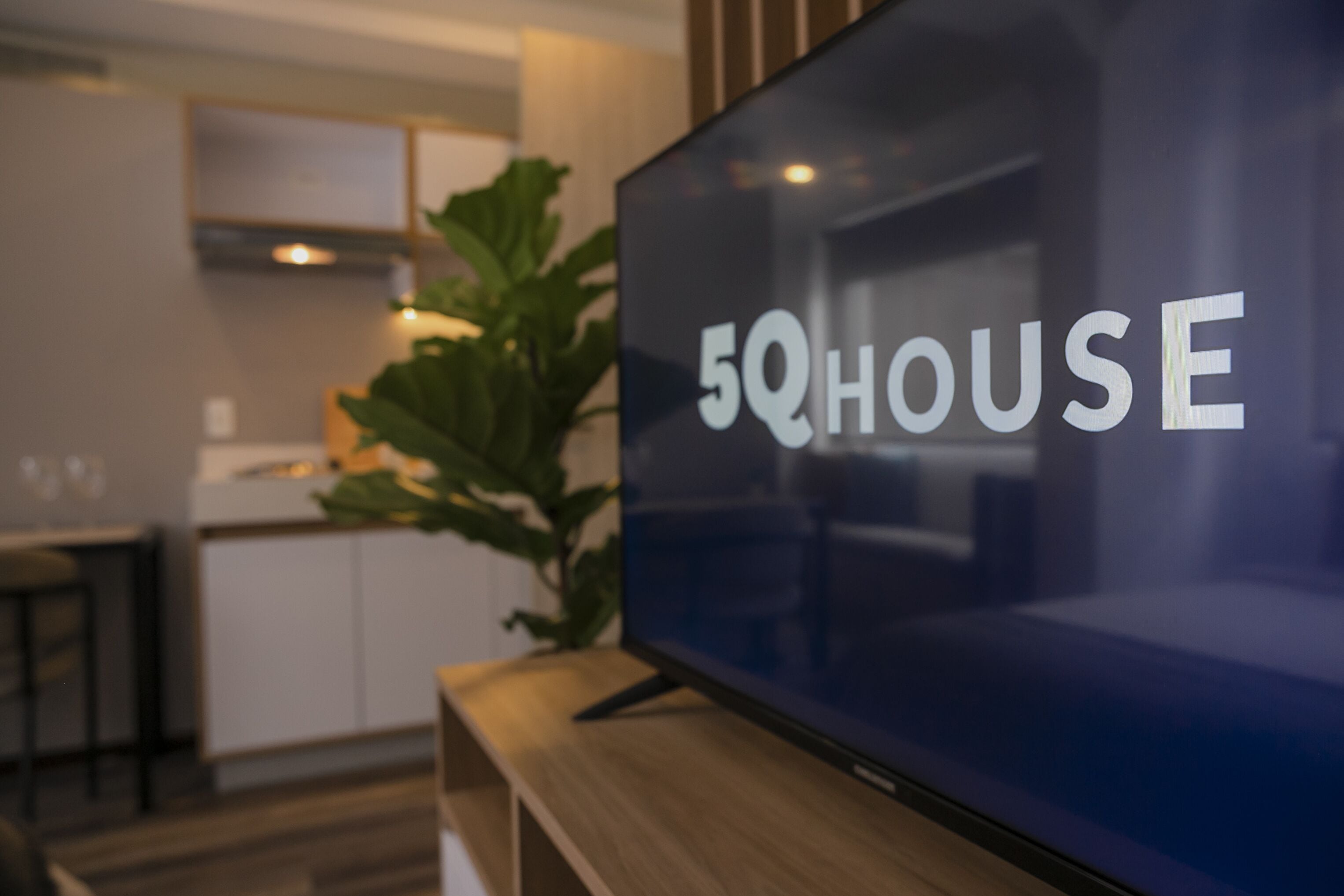 A modern living room with a flat-screen TV displaying the text "5QHOUSE".