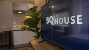 A modern living room with a flat-screen TV displaying the text "5QHOUSE".