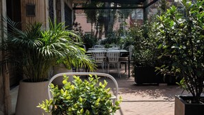 A covered outdoor area with a wooden table, potted plants, and a glass ceiling. - 5Q House Quinta Camacho (Bogotá)