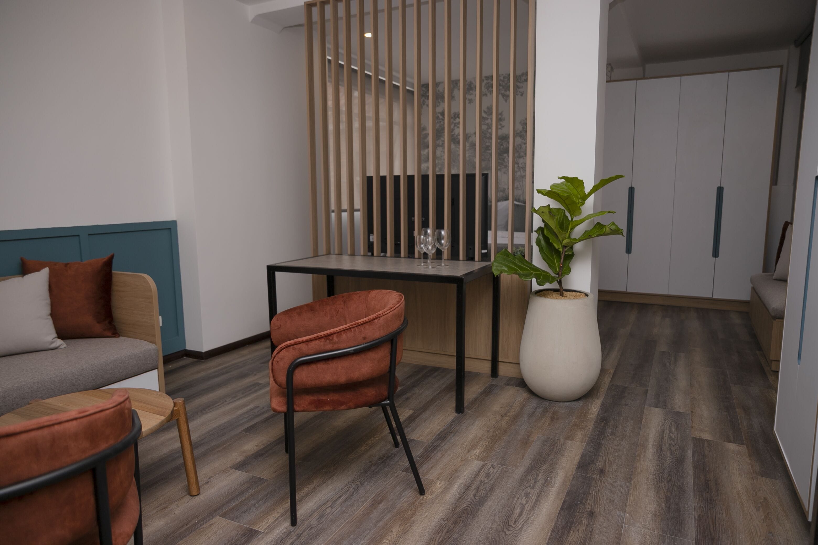 A modern room with a sofa, a dining table, a chair, a potted plant, and a wardrobe.