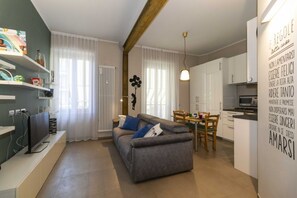 A modern living room with a sofa, a TV, and a dining area with a table and chairs.