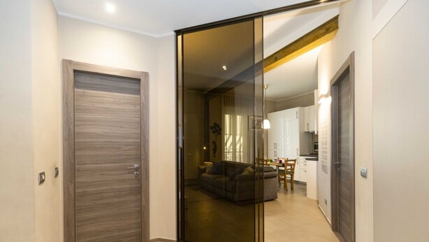 Un interno moderno con una porta scorrevole in vetro che dà su una zona living, una cucina e un'area pranzo.