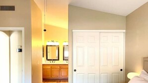 Un dormitorio con cama, mesita de noche, cómoda y puerta doble.