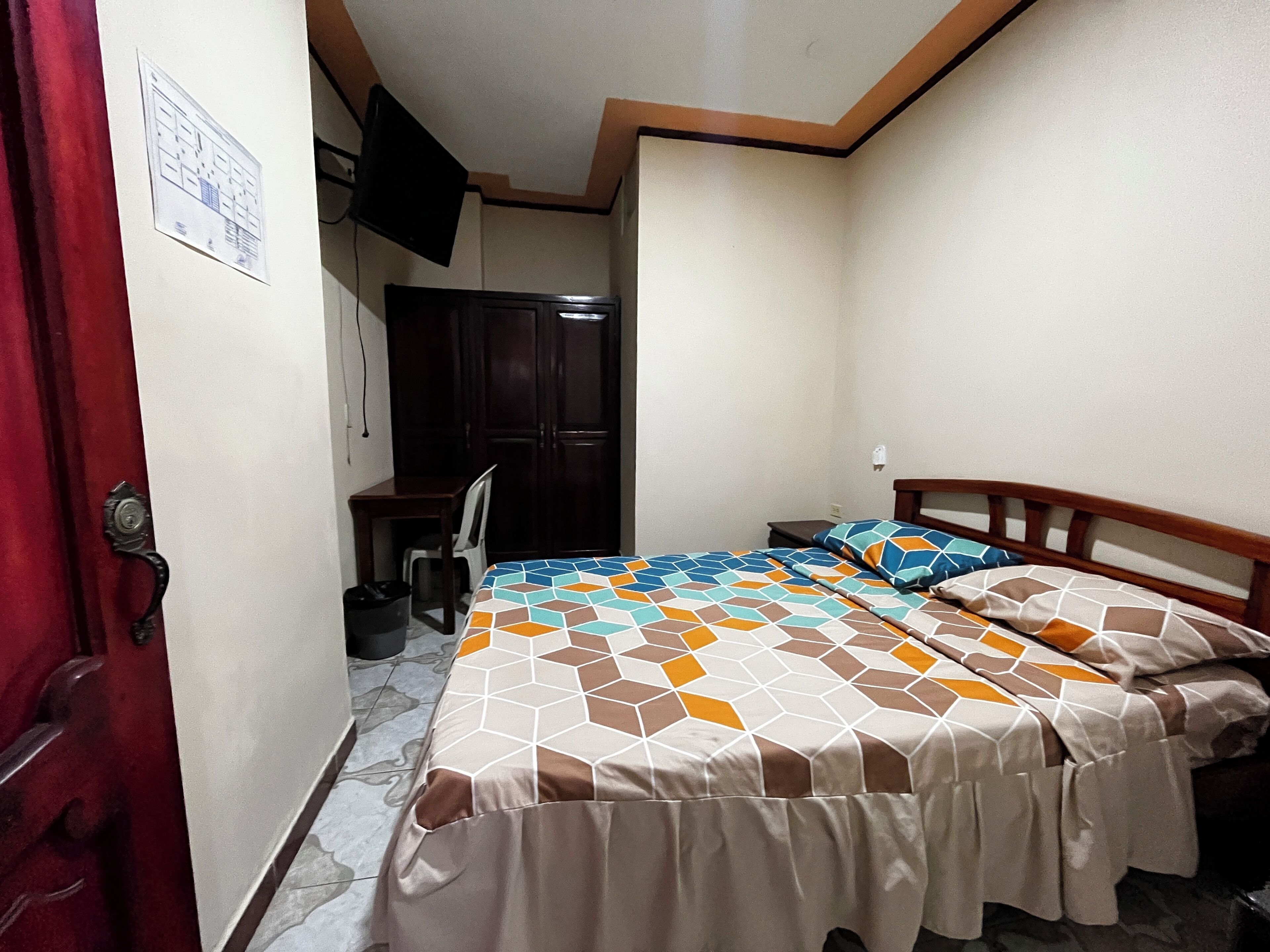 Un dormitorio con cama, escritorio, silla y armario.